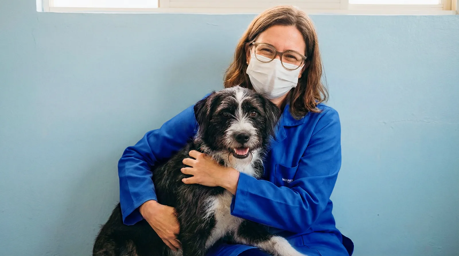 Médica veterinária da WeVets abraçando um cachorro